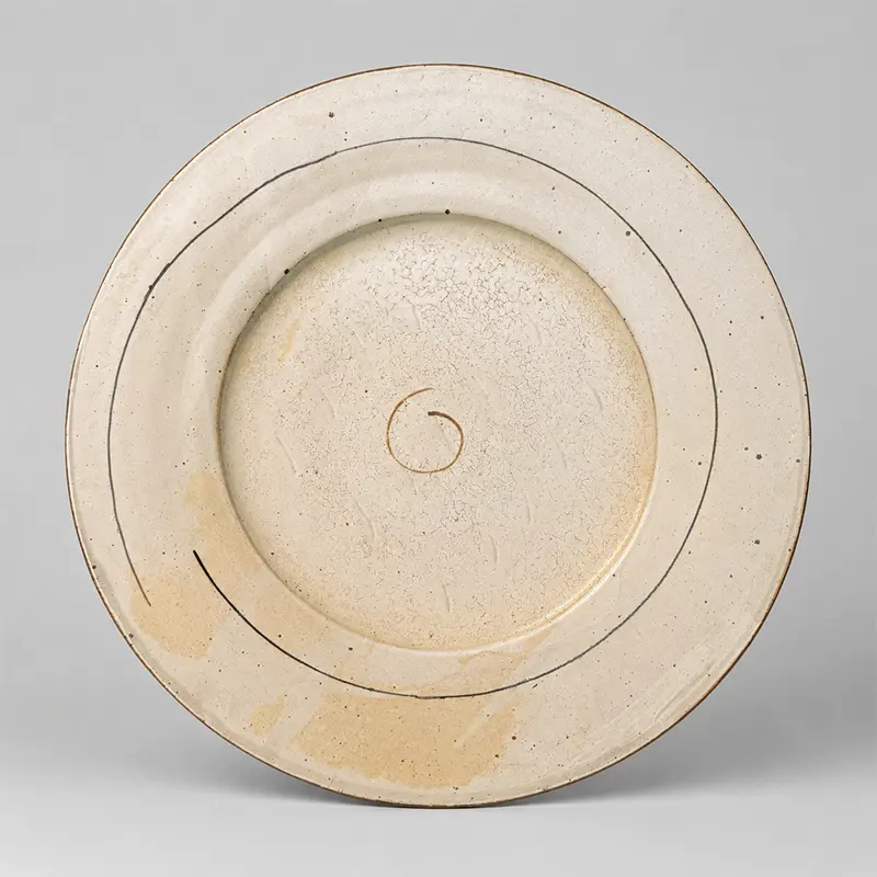 Large signed studio pottery stoneware charger with ivory crackle glaze, dark concentric lines, and central spiral motif on a neutral background.