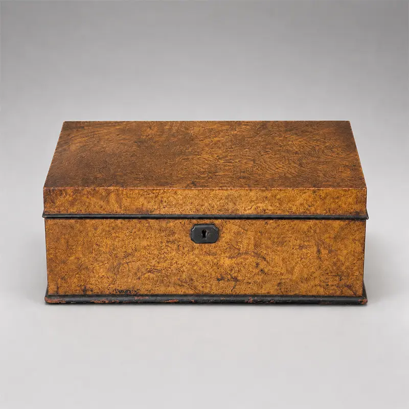 Antique burl wood box with richly figured golden brown grain, dark edging, and a centered keyhole escutcheon.